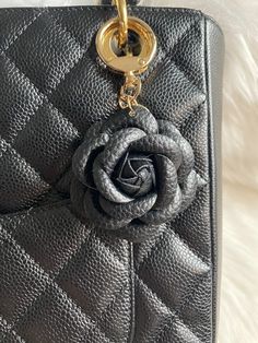 a black purse with a rose charm hanging from it