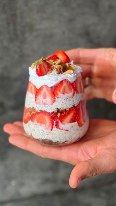 someone is holding up a small dessert in their hand with strawberries and nuts on top