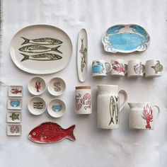 a table topped with plates and bowls filled with different types of fish designs on them