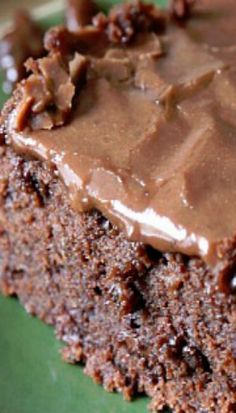 a close up of a piece of cake on a green plate with chocolate frosting