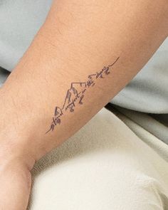 a person's arm with a tattoo on it that has mountains and stars in the middle