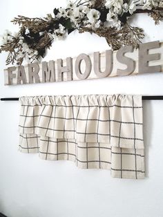 the word farmhouse spelled in metal letters on a white wall next to window valance