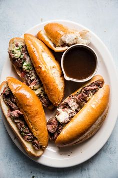 three sandwiches on a plate with dipping sauce