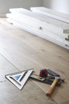 tools are laying on the floor next to plywood planks and paintbrushes