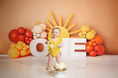 a baby standing in front of a cake with the word love spelled out on it