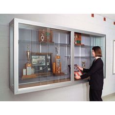 a woman is looking into a glass display case