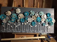 an art piece with flowers on it sitting on top of a wooden easel in a workshop