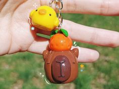 a hand holding a keychain with a bear and duck on it