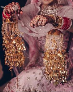 a woman in a pink dress holding some gold jewelry