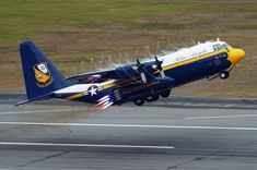 a blue and white airplane taking off from an airport runway