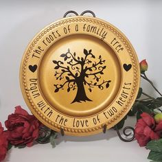 there is a golden plate with a tree on it and some red flowers around it