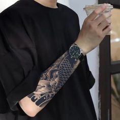 a man with a dragon tattoo on his arm holding a piece of food in his hand