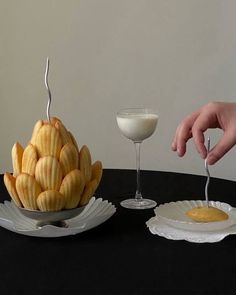 a person is reaching for some food on a plate with a fork and glass next to it