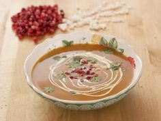 a bowl filled with soup and garnished with pomegranates on a wooden table