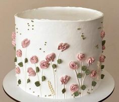 a white cake decorated with pink flowers and pearls