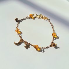 This Beautiful 14k Moon and Star Charm Bracelet is perfect for anyone who loves the moon, stars, and all things astronomy-related! The bracelet has the personalized color options of bronze, pink, or green beads of your choosing and two astronomy pendants; one star and one moon charm. It also comes with a moon and star charm which is a perfect and unique gift for any stargazer in your life! This Beautiful moon and stars, gold charm bracelet is also a part of the Astronomy Collection which is full Adjustable Celestial Charm Bracelets, Adjustable Celestial Charms Bracelet, Bohemian Gold Bracelet With Moon Charm, Adjustable Star-shaped Celestial Bracelets, Adjustable Celestial Star Bracelet, Adjustable Celestial Bracelets With Star Charm, Adjustable Gold Celestial Charm Bracelet, Celestial Charm Bracelet With Star Charm As Gift, Celestial Star Charm Bracelet Gift