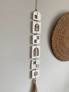 a wall hanging with letters and tassels on it next to a wicker basket