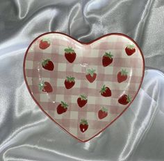 a heart shaped plate with strawberries on it sitting on a tablecloth covered surface