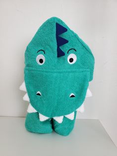 a green stuffed animal with a blue hat on it's head and one eye open