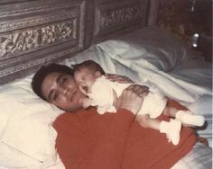 a man laying in bed holding a baby