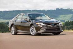 a brown toyota camry parked on the side of a road with mountains in the background