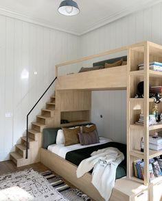 a bedroom with a bunk bed and bookshelf next to the stairs in front of it