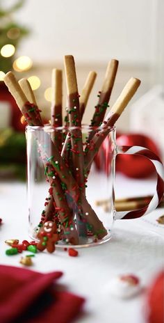 a glass filled with candy canes and sprinkles next to a christmas tree