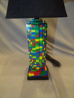 a lamp made out of legos sitting on a white sheet with a black shade