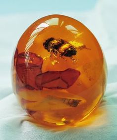 an orange glass ball sitting on top of a white cloth