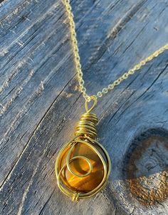 The natural, round tiger's eye cabochon crystal is hand-wrapped in gold wire with a looped, outer wrap design.  The pendant can also add either a gold or a silver chain to your order for a beautiful necklace!  Tiger's Eye is believed to bring balance and harmony, rid of fears, and provide courage with decisions to protect those who wear this crystal. Check out my Etsy shop for other Crystal Wrapped pendants! & IG: CrystalWrappedCreations - to see behind the scenes, and reserve items before poste Gold Cabochon Round Beads Jewelry, Adjustable Amber Wire Wrapped Jewelry, Hand Wrapped Gold Necklace With Copper Wire, Spiritual Round Wire Wrapped Necklace, Adjustable Gold Hand-wrapped Necklace, Adjustable Hand Wrapped Gold Necklace, Gold Wire-wrapped Pendant Crystal Necklaces, Gold Wire-wrapped Pendant Crystal Necklace, Gold Wire-wrapped Crystal Pendant Necklace