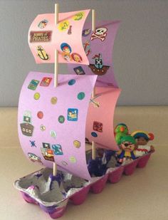 a pink pirate ship with lots of stickers on it's sails is sitting in some cupcakes