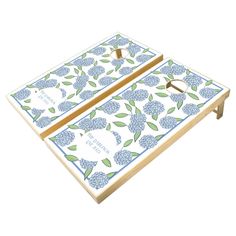 two pieces of blue and white floral design with name on each side, sitting on top of a wooden table