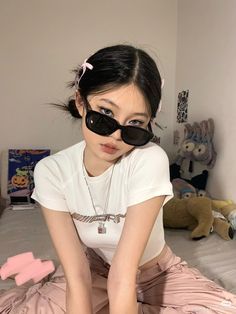 a woman wearing sunglasses sitting on top of a bed