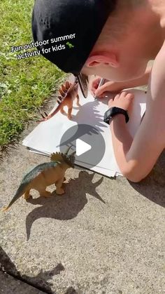 a young boy is writing on paper with dinosaurs in the background