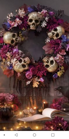 a decorated wreath with skulls and flowers on top of a table next to an open book