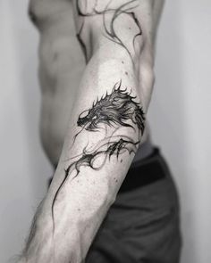 a black and white photo of a man's arm with a dragon tattoo on it