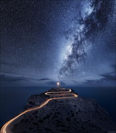 the night sky is filled with stars and light trails as seen from an island in the ocean