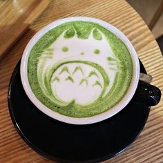 a cup of green tea with an image of a cat drawn on the foam in it