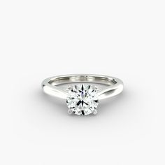 a white gold engagement ring with a round brilliant cut diamond in the center, on a plain surface