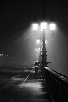 a person is walking down the street at night with an umbrella in hand and some lights on