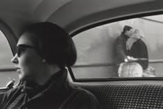 a woman sitting in the back seat of a car next to a man on a television screen