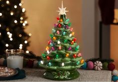 a green ceramic christmas tree sitting on top of a table next to a lit candle