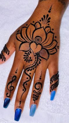 a woman's hand with henna tattoos and blue nail polishes on it