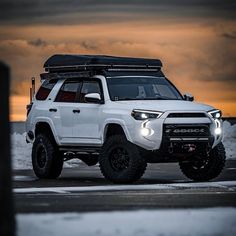 a white toyota 4runner is parked in the snow