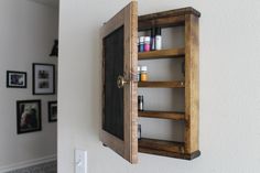 an open wooden cabinet mounted to the side of a wall next to a doorway with pictures on it