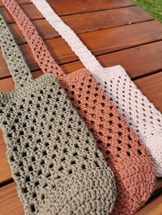 three crocheted bags sitting on top of a wooden table