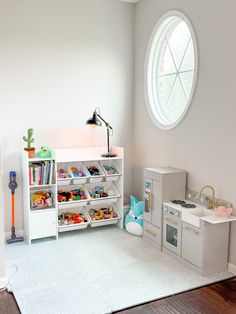 a play room with toys, bookshelves and other items in the corner near a round window