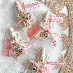 three small bottles with pink ribbons and tags attached to them sitting on a white rug