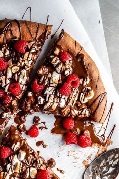 a chocolate pizza topped with raspberries and nuts