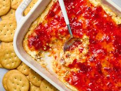 a casserole dish with cheese and sauce in it, surrounded by crackers